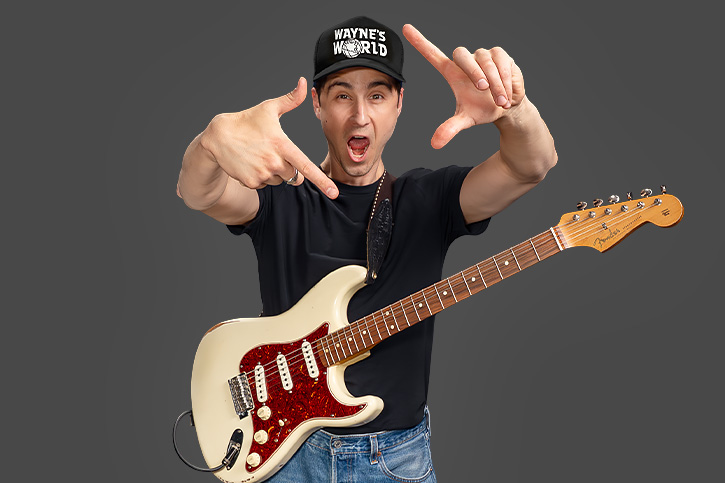 Alex Leach wearing his guitar and a Wayne's World hat